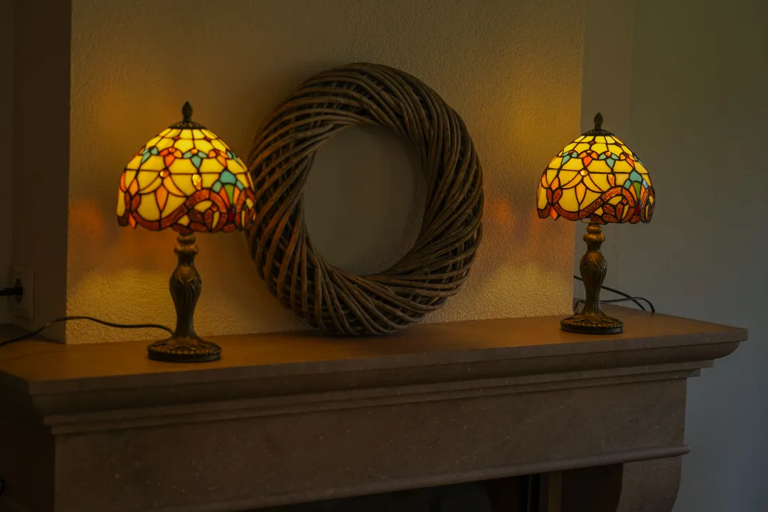 Twee brandende Tiffany-lampen op een schouw